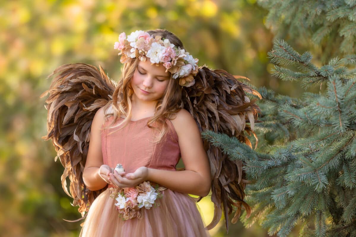 young fairy with wings holding a bird in spring