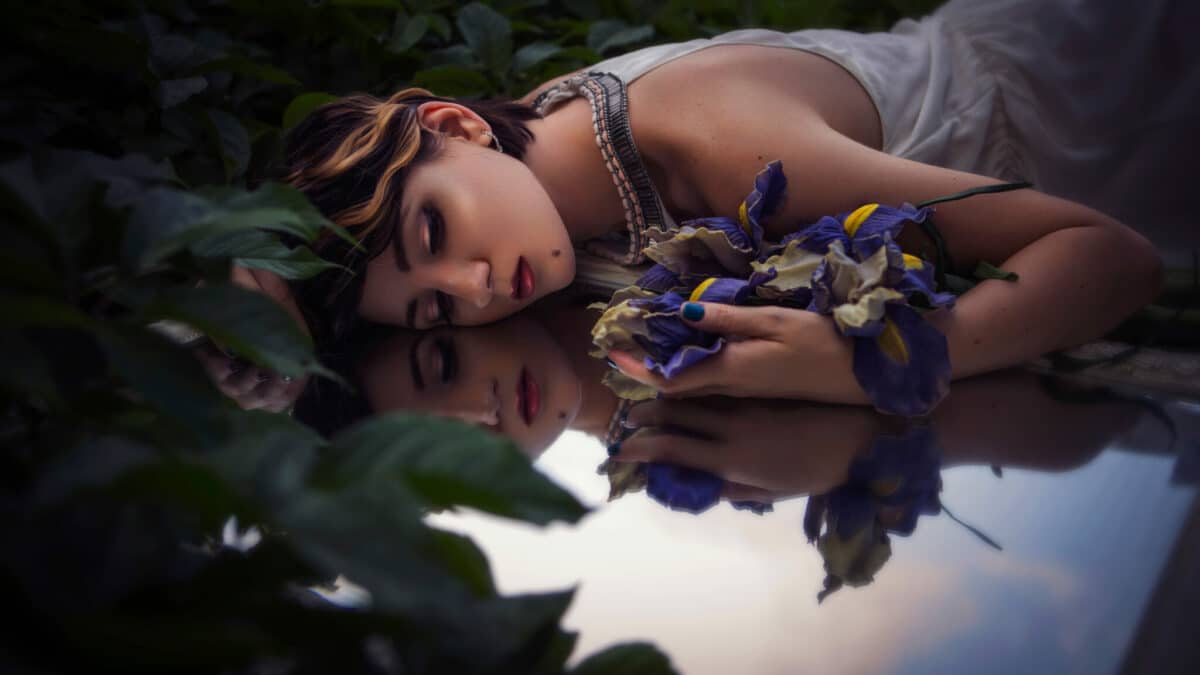 Beautiful brunette woman sleeping in the meadow holding flowers
