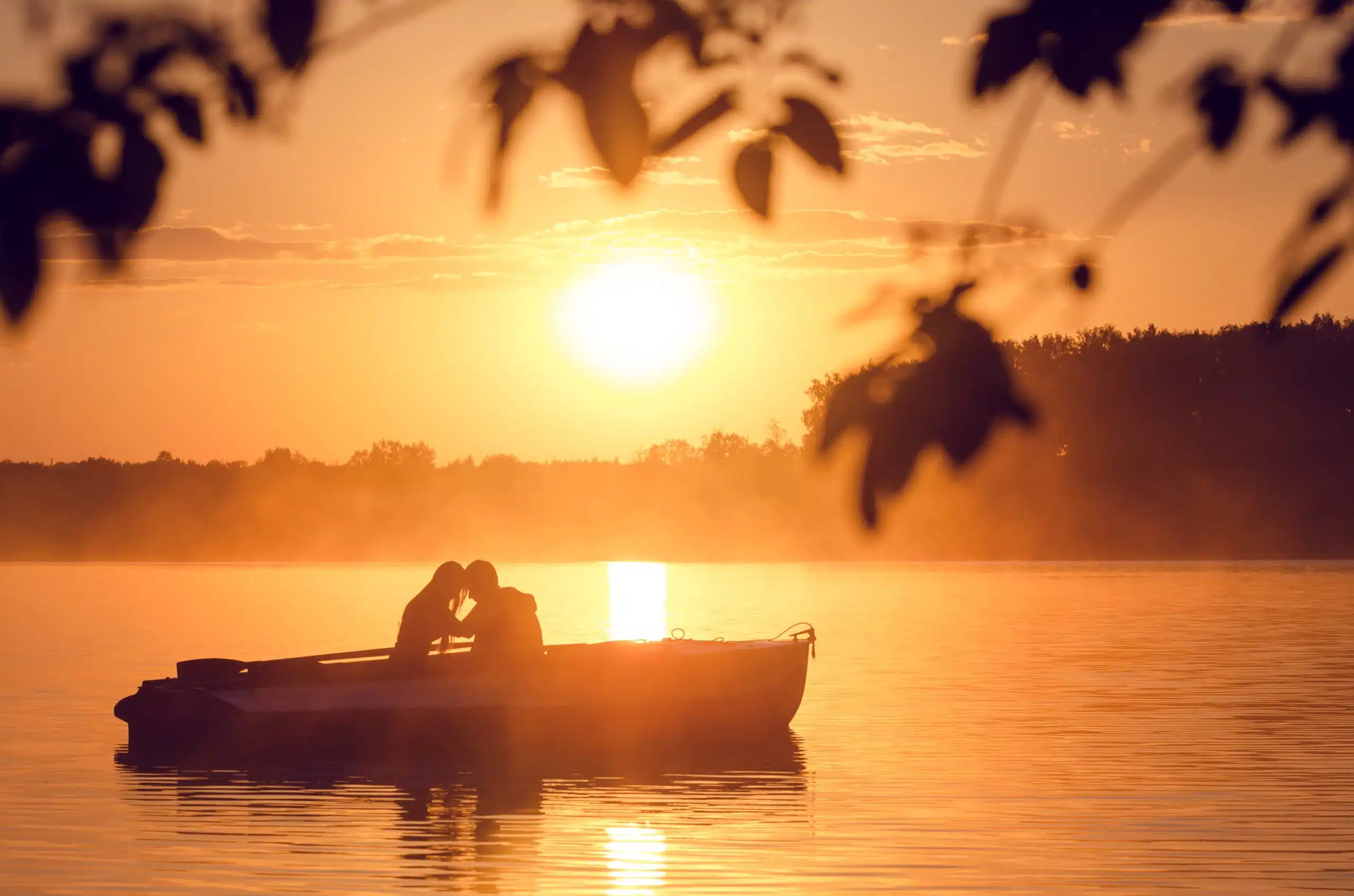 Silhouette of couple on boat and romantic golden river sunset