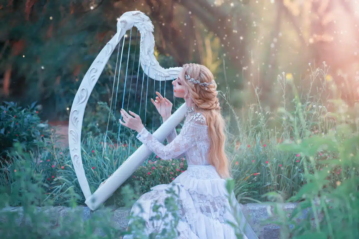 mysterious forest nymph plays on white harp in the forest