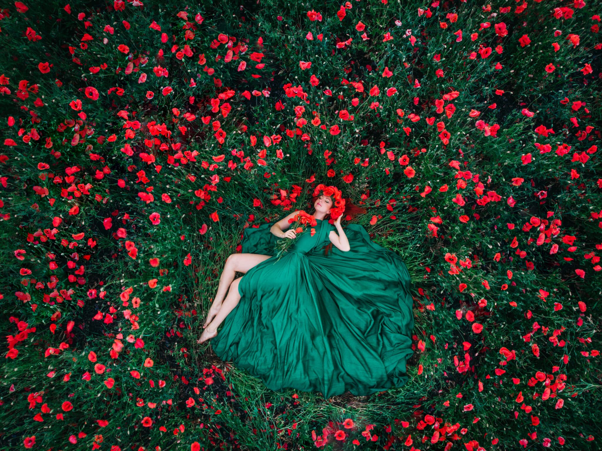 Beautiful woman lies in a poppy field, top view.