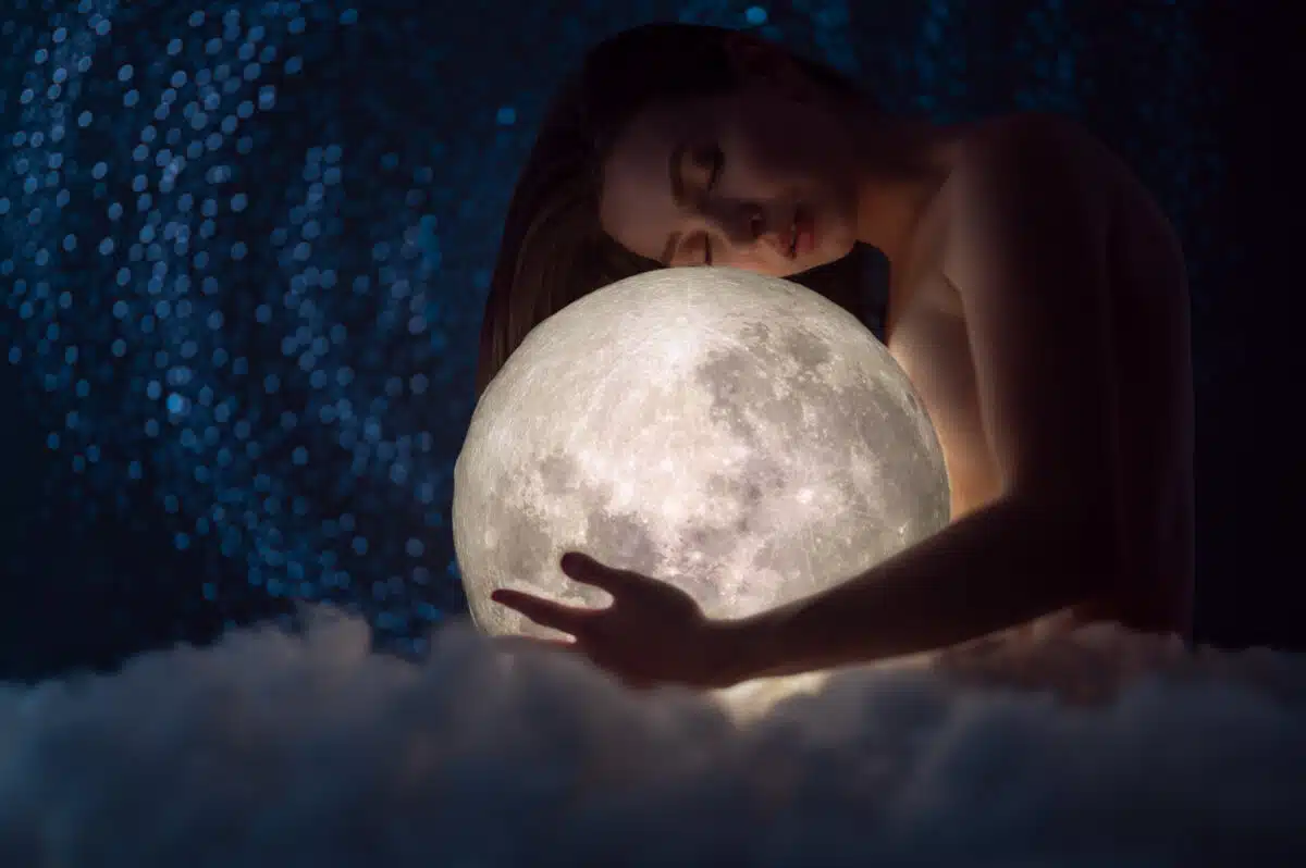 a goddess with the moon in her hands with the milky way stars behind her