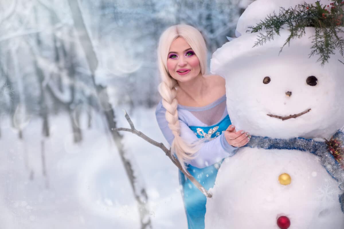 beautiful princess standing next to a snowman in the winter forest