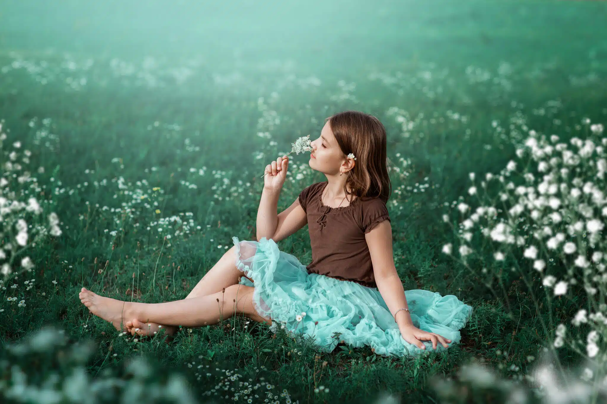 A 10-year-old girl walks in a field with white flowers. 