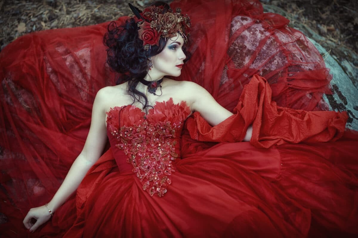 The fairy in a red dress is lying on a rock