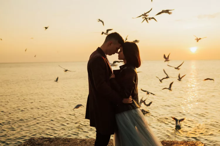 Young passionate couple embracing at amazing sunset over sea