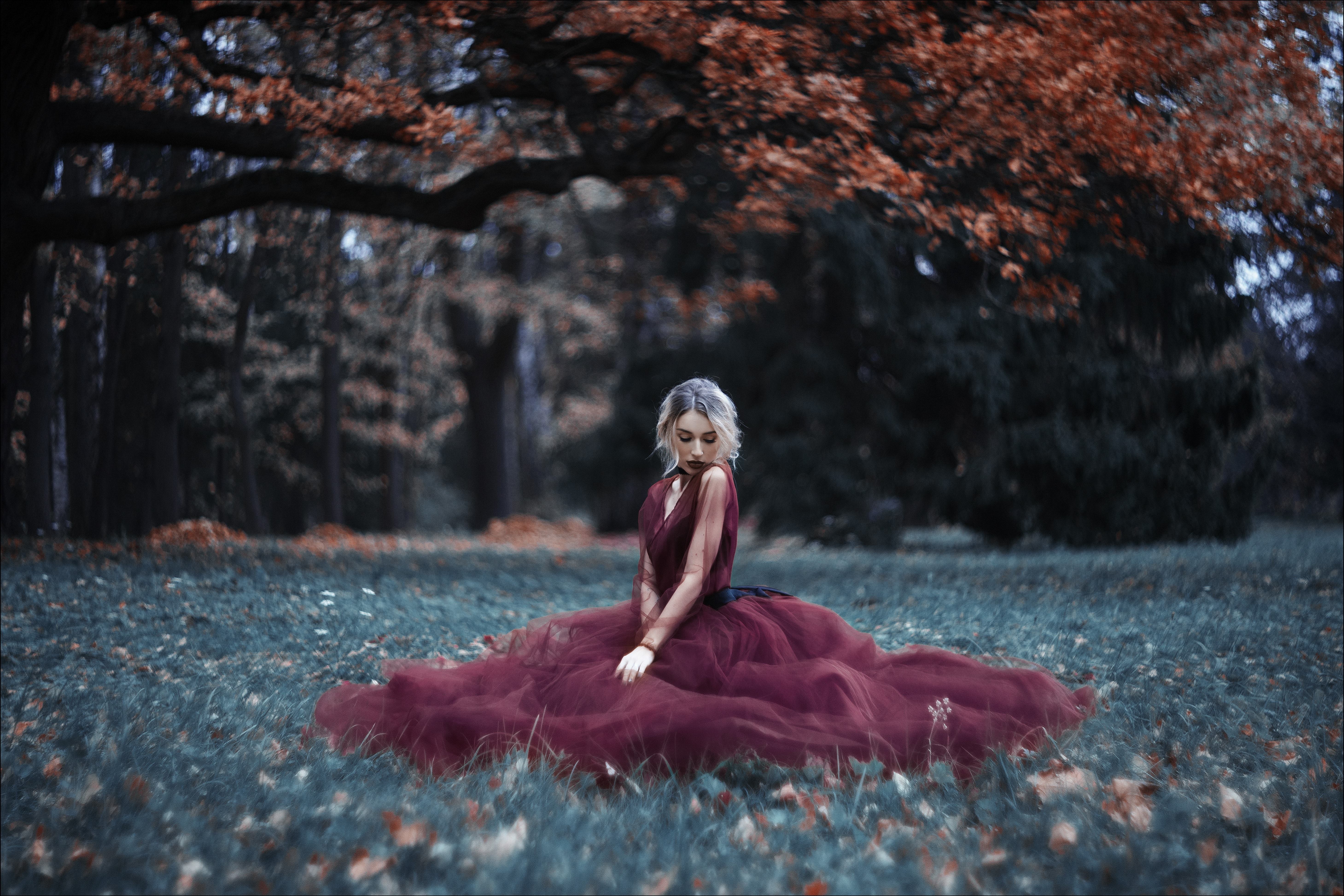 Young fragile girl in a red long dress on the background of the