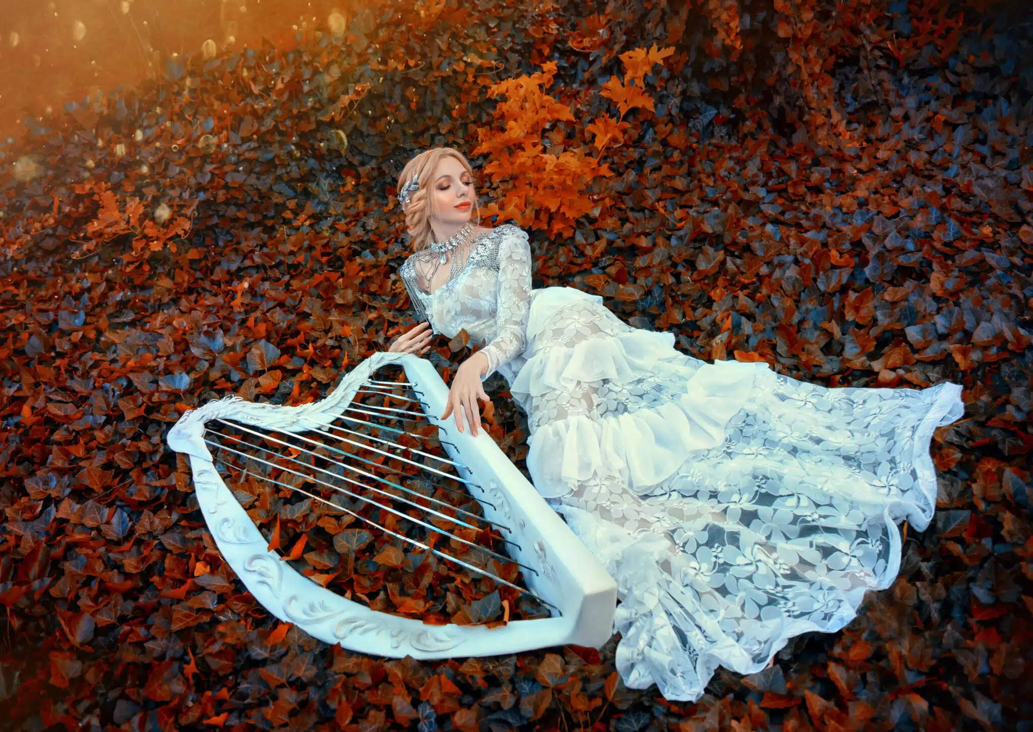 excellent princess with blond hair in long lace vintage dress lies on red dark leaves