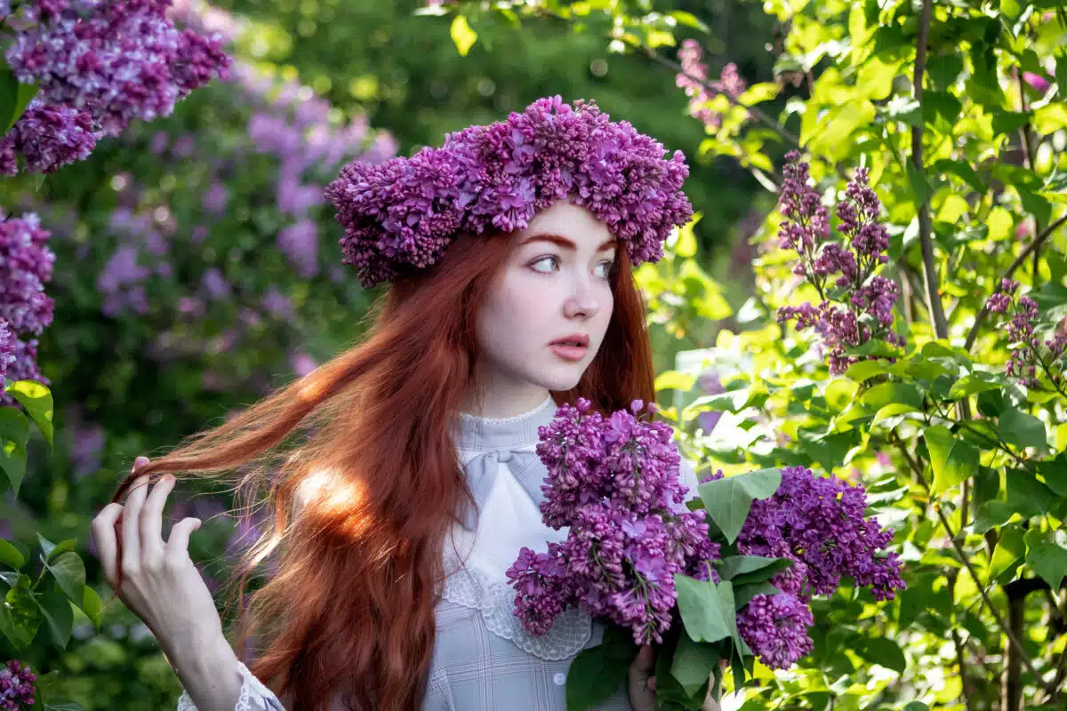 young girl with long red hair with a wreath of lilacs on her head