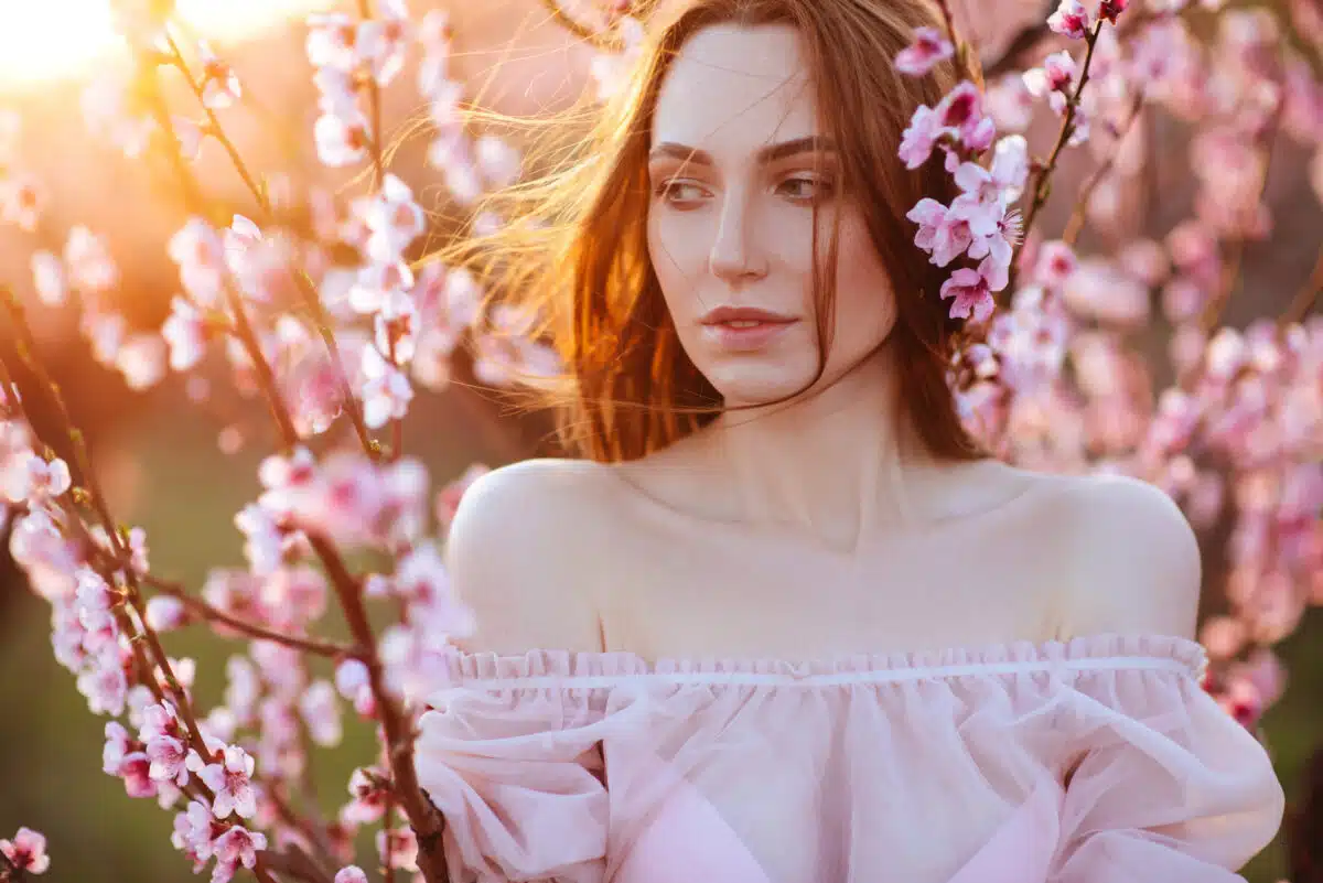 Beautiful young girl under the flowering pink spring tree