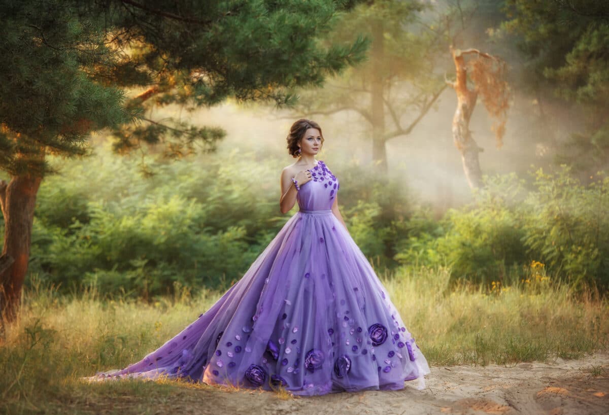 Beautiful, young, brunette in a luxurious, purple, long dress. Fairy Photo. Creative toning. Queen walking in the fairy forest.