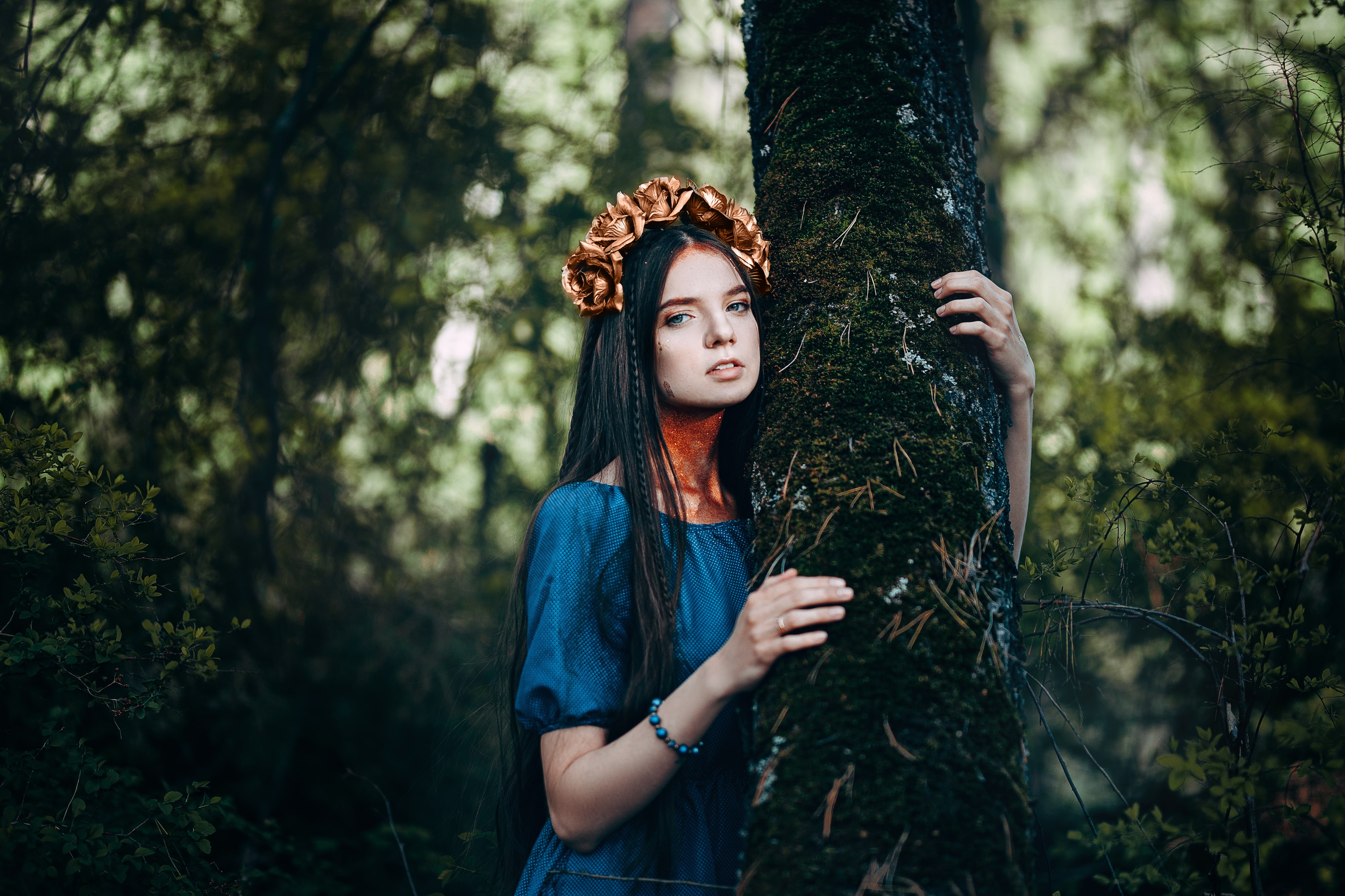 portrait of beautiful brown-haired woman in a long blue dress, with a wreath of golden roses on her head, in the fairy forest, golden paint shimmer on her neck fantasy concept