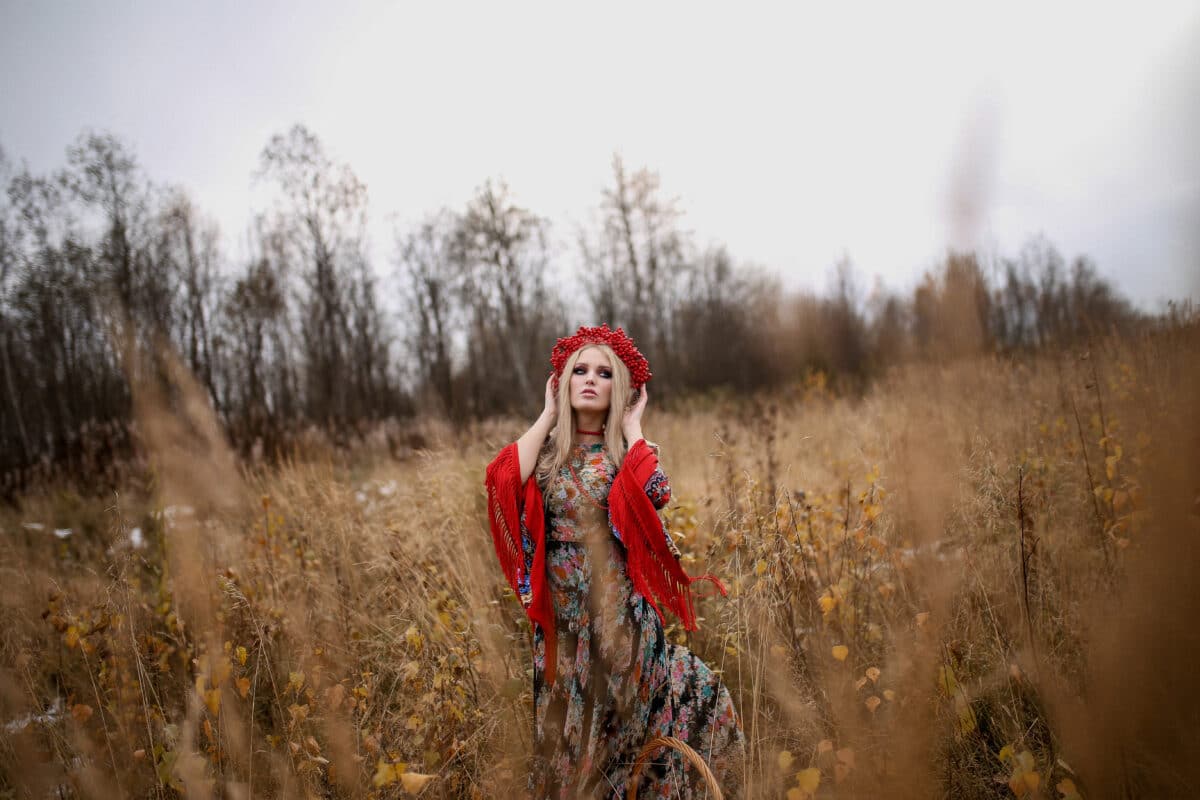 A beautiful woman with long blond hair and blue eyes standing in the field
