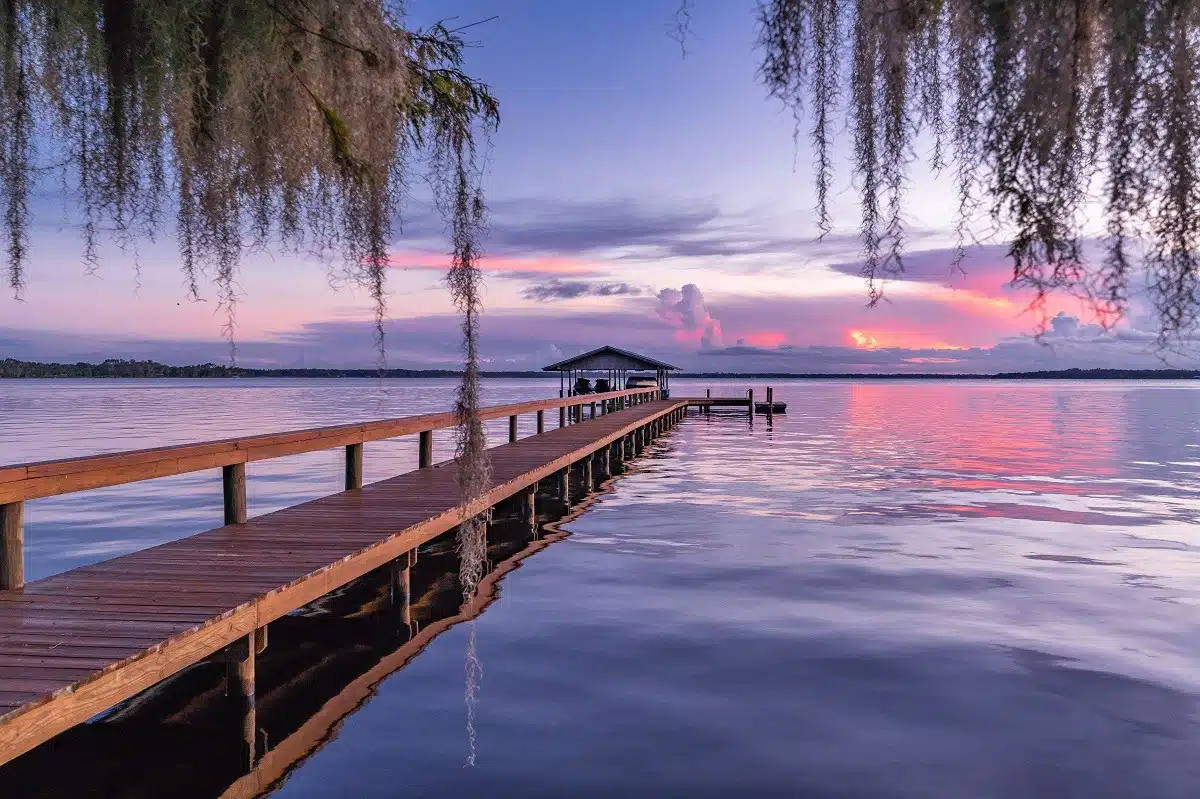 wooden dock at lake, beautiful purple sunset in the background