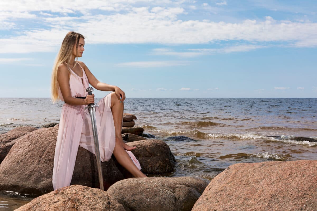 Young woman in a long dress posing on rocks on the sea coast
