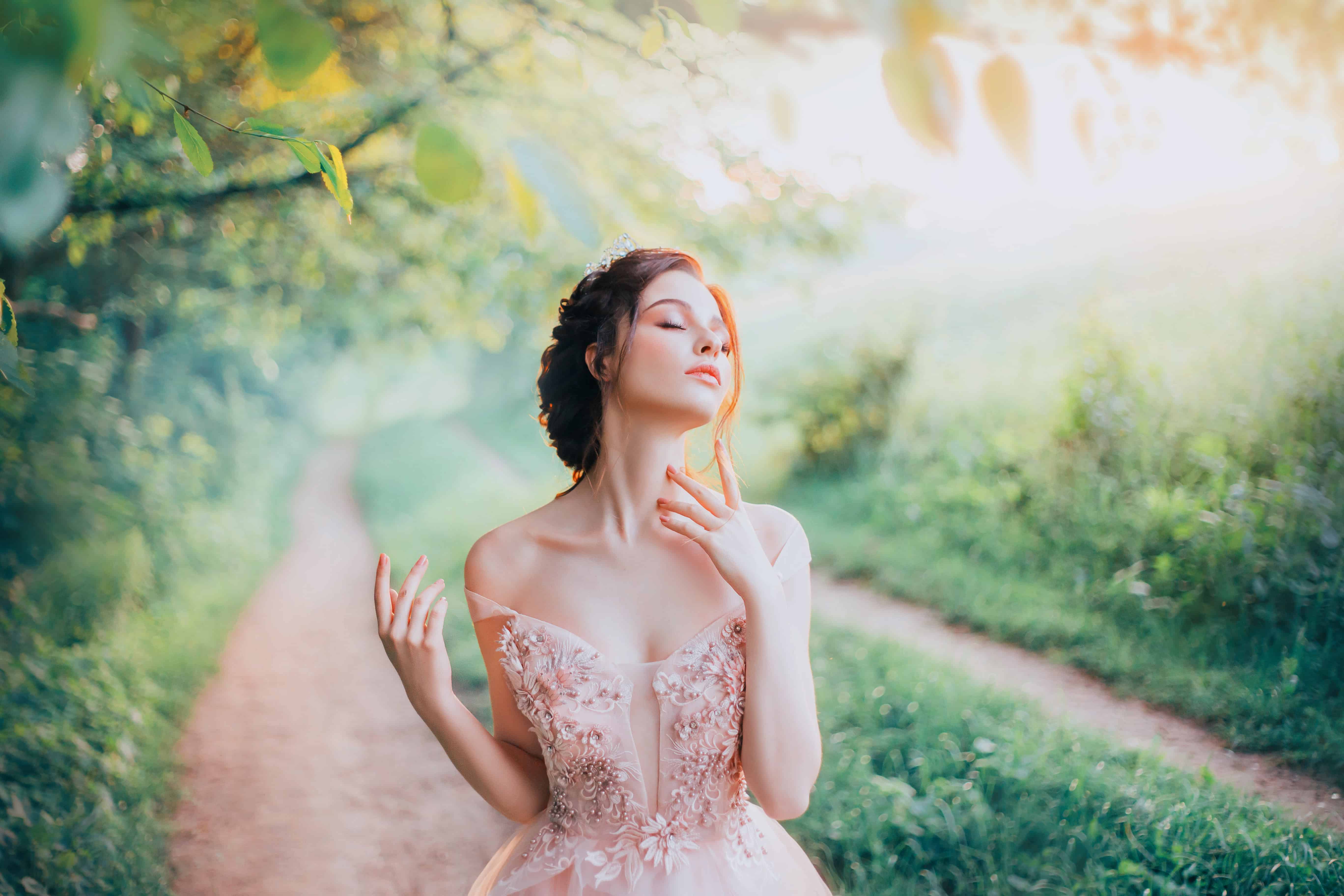 charming goddess of the spring forest stands on a narrow path and breathes in the sweet smell of nature, pleasure in motion, lady with her eyes closed strokes her beautiful neck with her fingertips