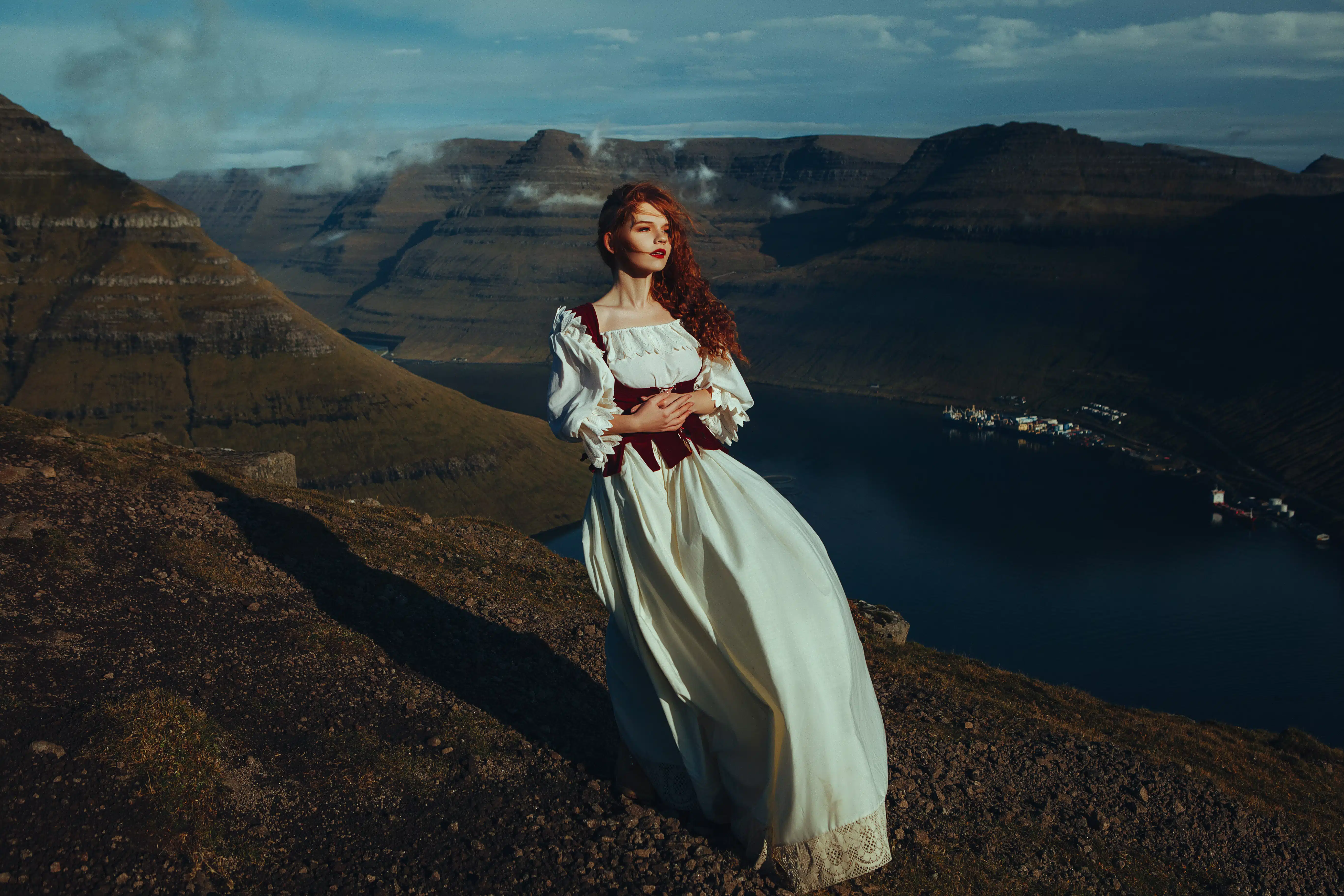 Beautiful red-haired girl on the top of the mountain over the ocean in Faroe Islands