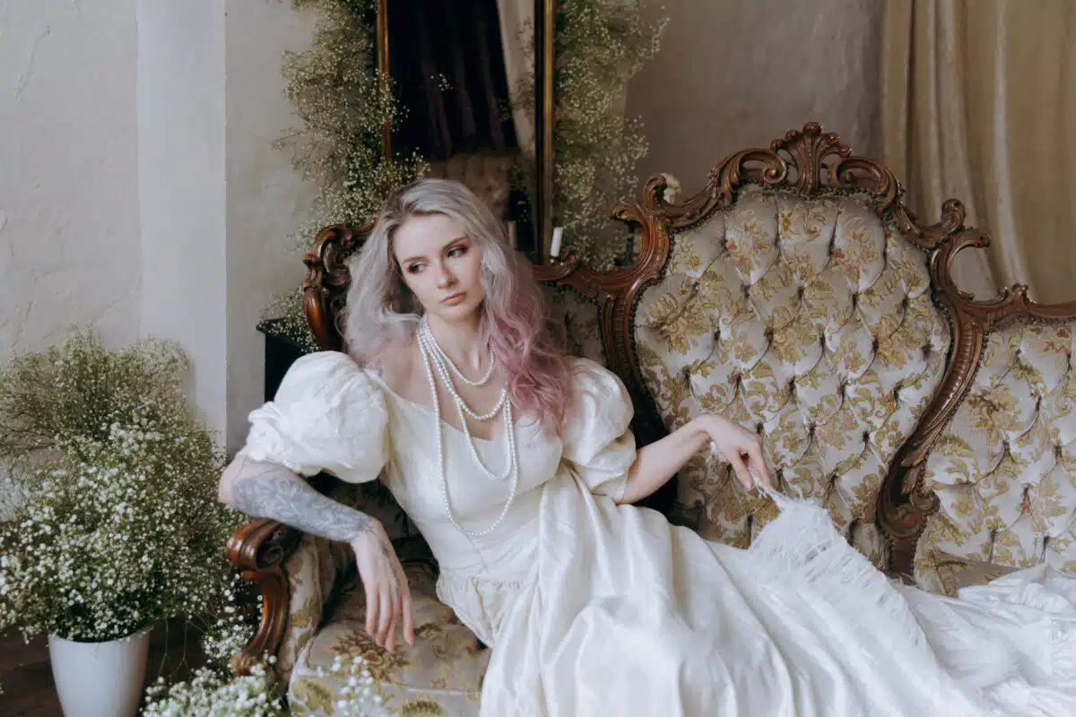 A luxurious girl with a beautiful make-up and hairstyle in a vintage vintage dress woke up in the morning in bed and sits on the sofa at the piano and poses as a model
