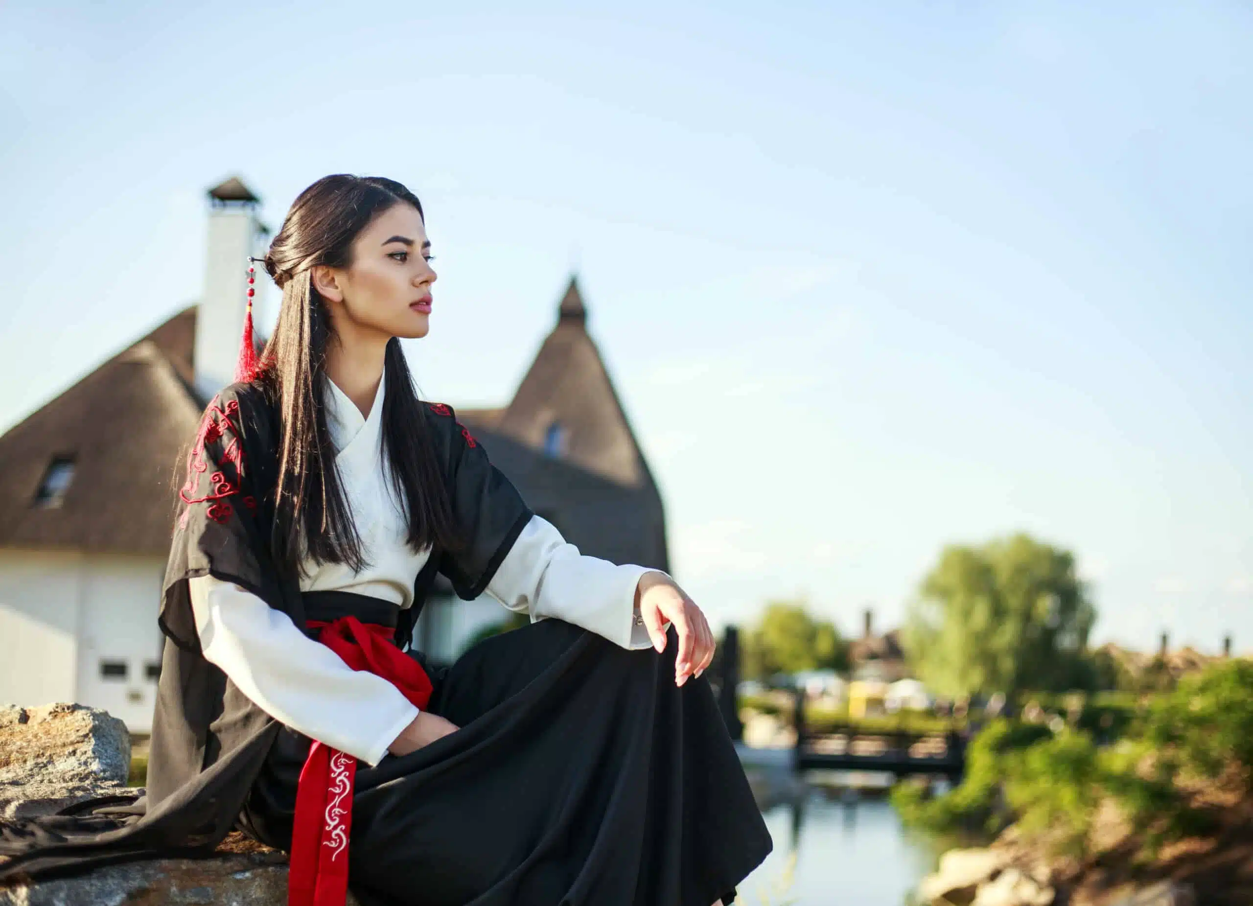Pensive asian girl looking with hope sitting on stone in traditional clothes.