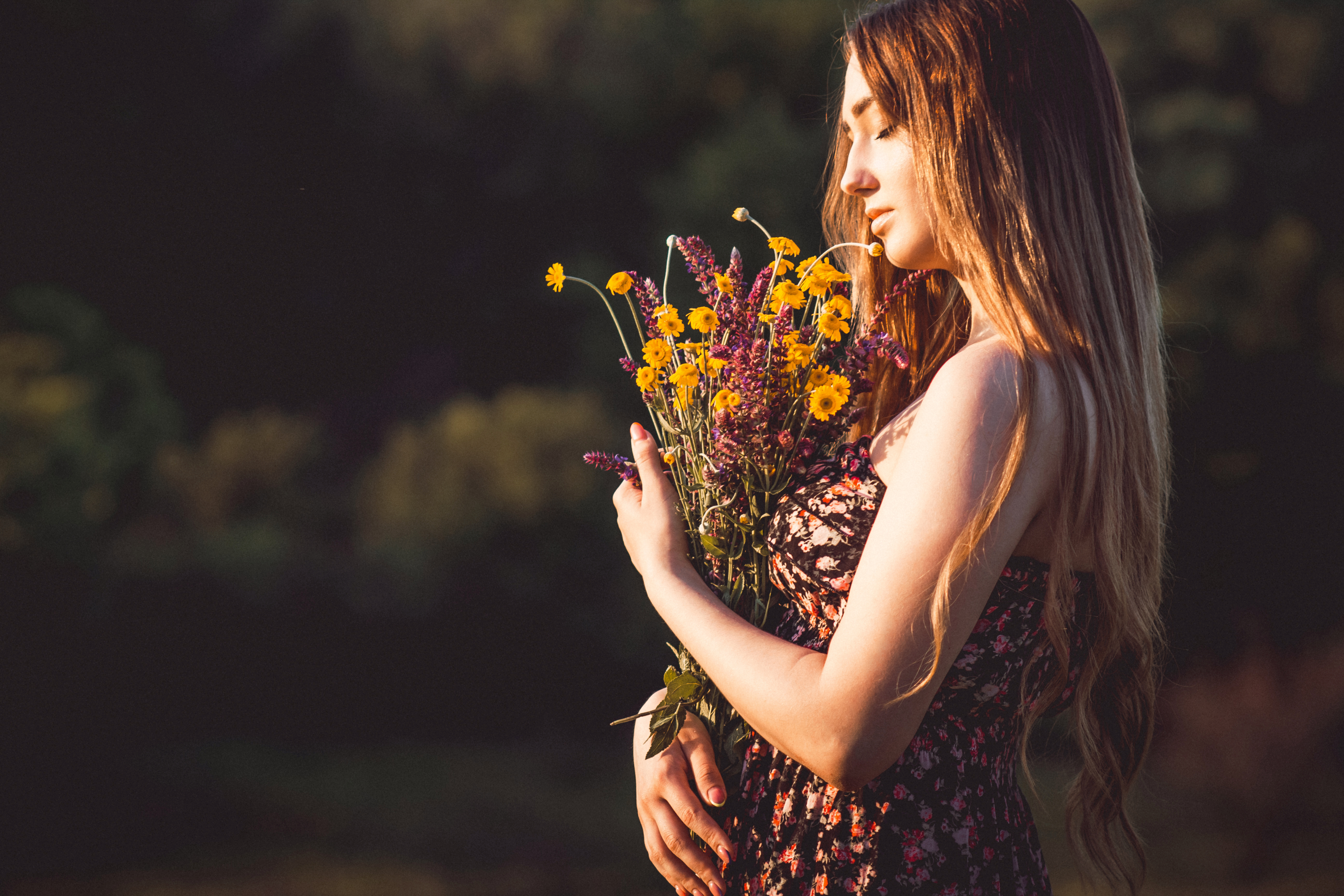 beautiful girl with bouquet of wildflowers on the meadow in summertime