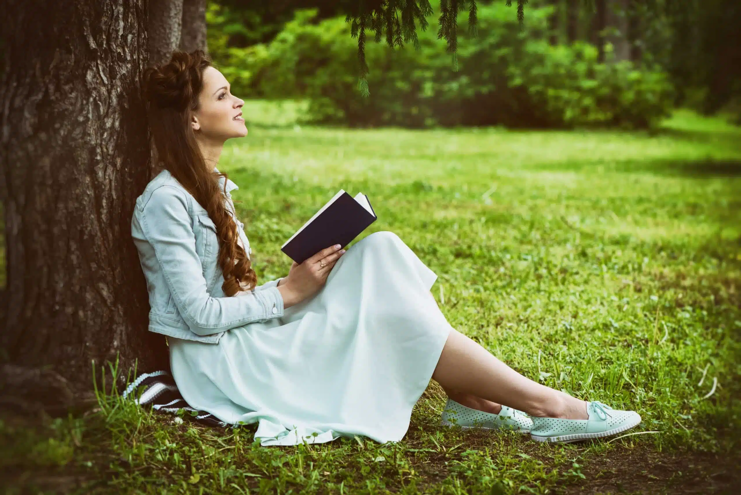 Beautiful young woman reading a book in the park.