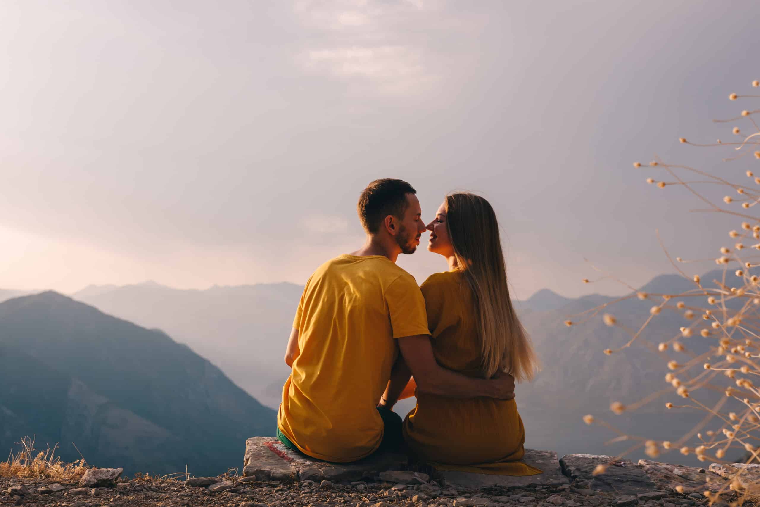 Romantic young couple kissing at sunset, mountains on background