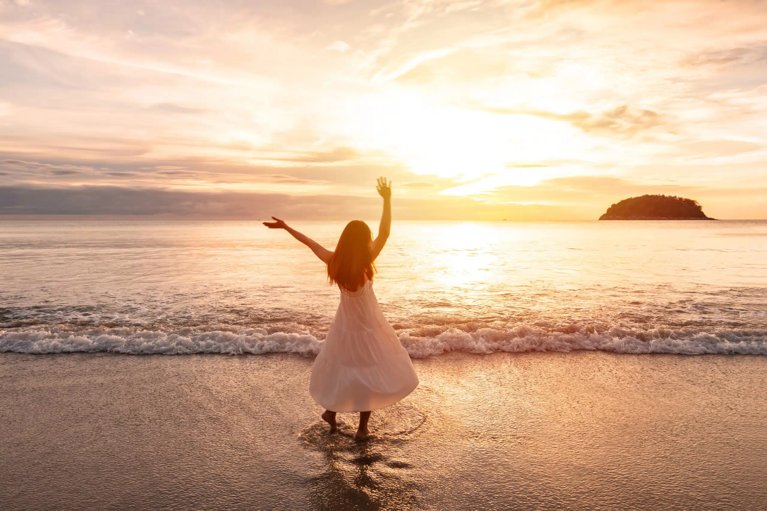 Young woman dancing and enjoying beautiful Sunset on the tranquil beach.