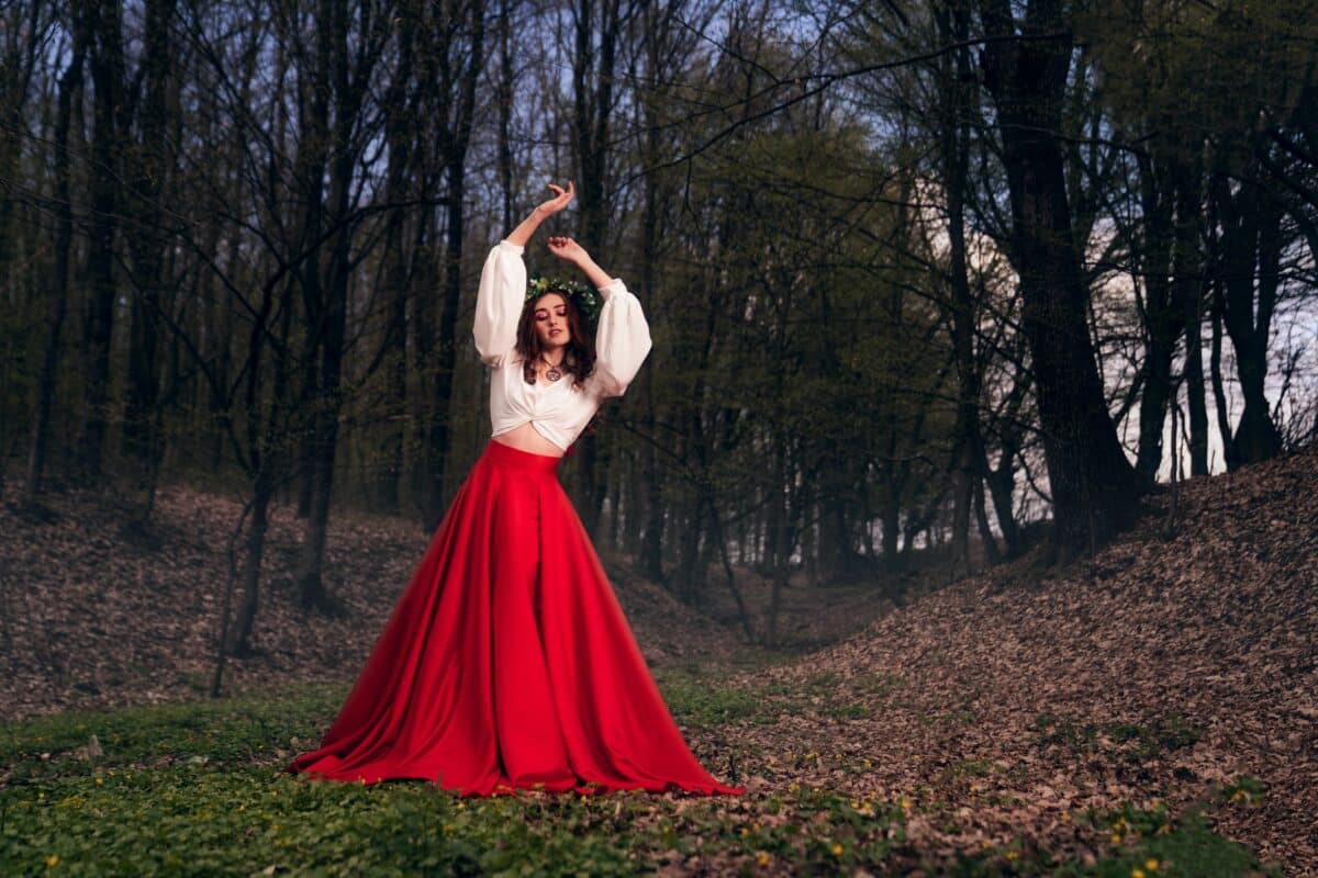 Fashionable young woman wearing a long red skirt a forest