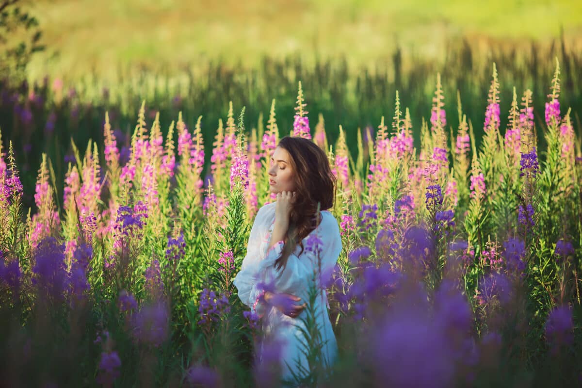 Beautiful girl dressed in white enjoying the flowers on the lavender field