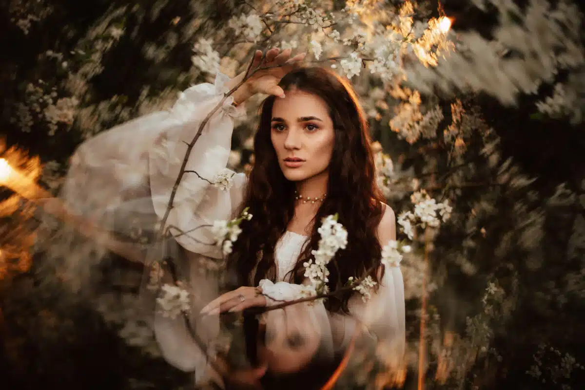 Portrait of a romantic girl, like a forest nymph, in a blooming garden with elements of phantasmagoria. The concept of fantasy, fairy tales.