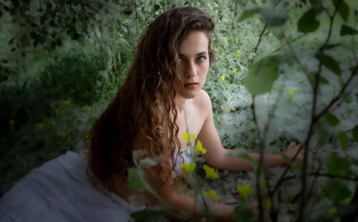 beautiful natural woman with yellow primrose flowers in nature