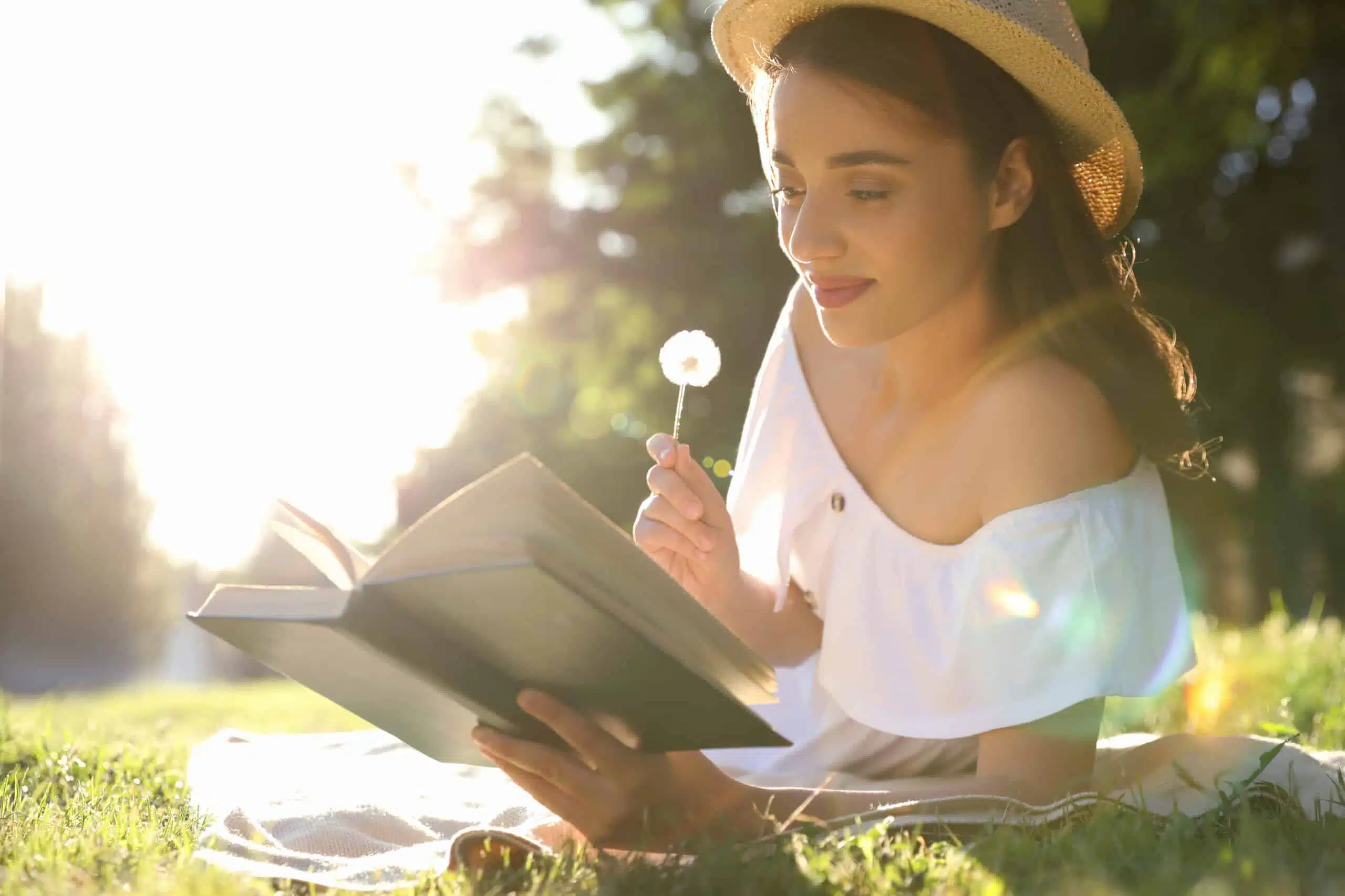 Beautiful young woman reading book in park