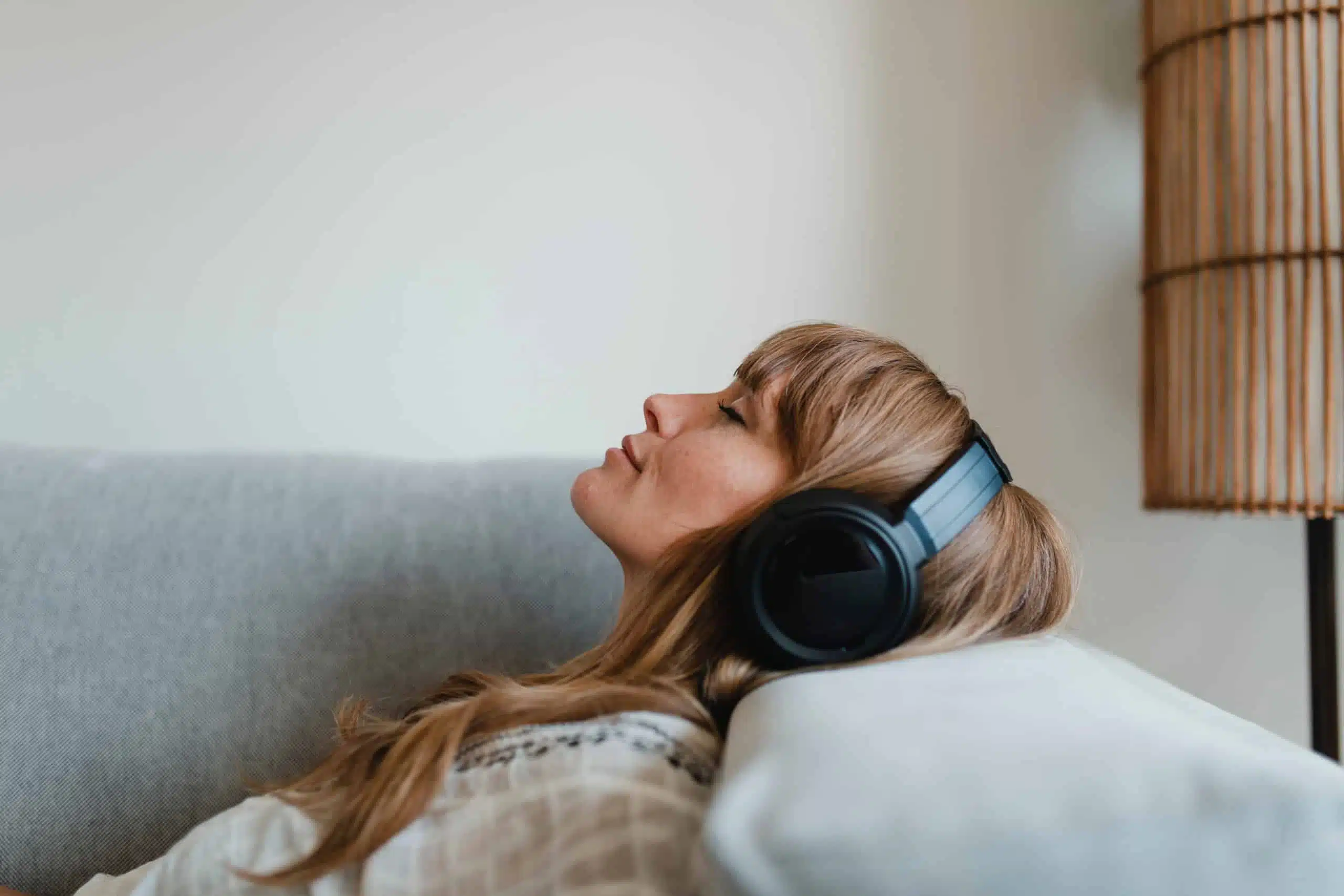 Woman relaxing on sofa, listening to music at home.