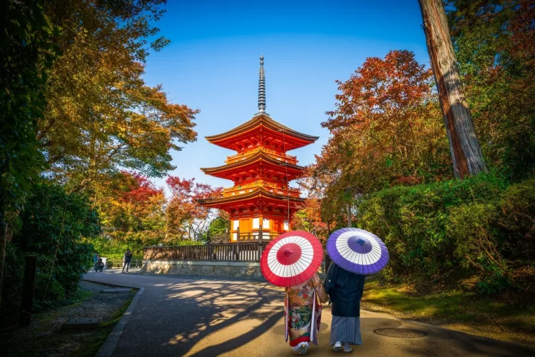 traditional Japanese couple walking toward the Koyasu Pagoda in autumn season