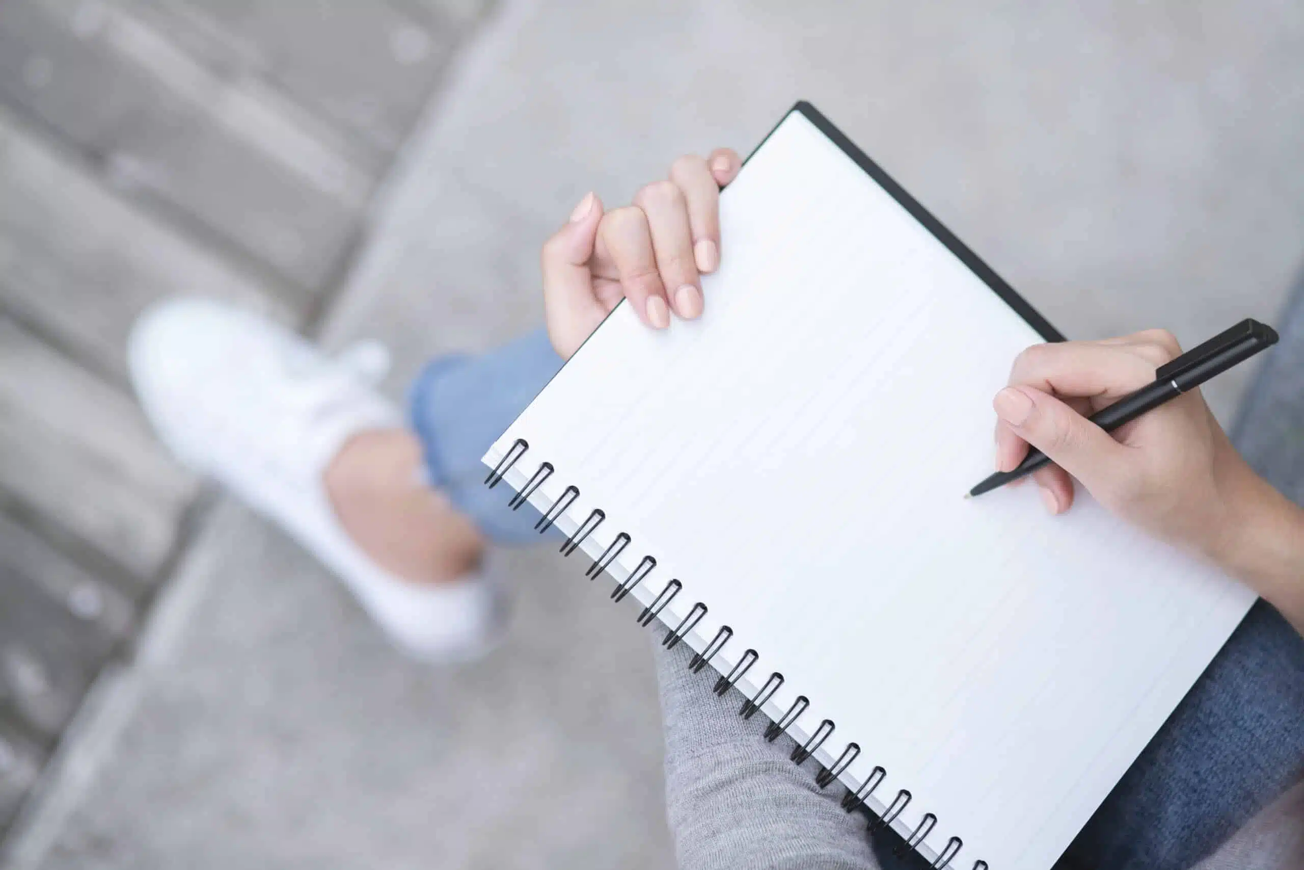 female hands with pen writing on notebook while sitting