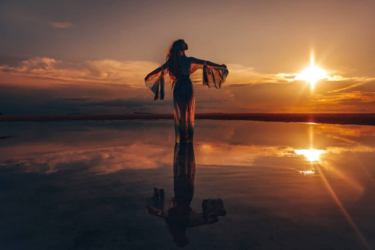 silhouette of a mysterious woman dancing on the water at sunset