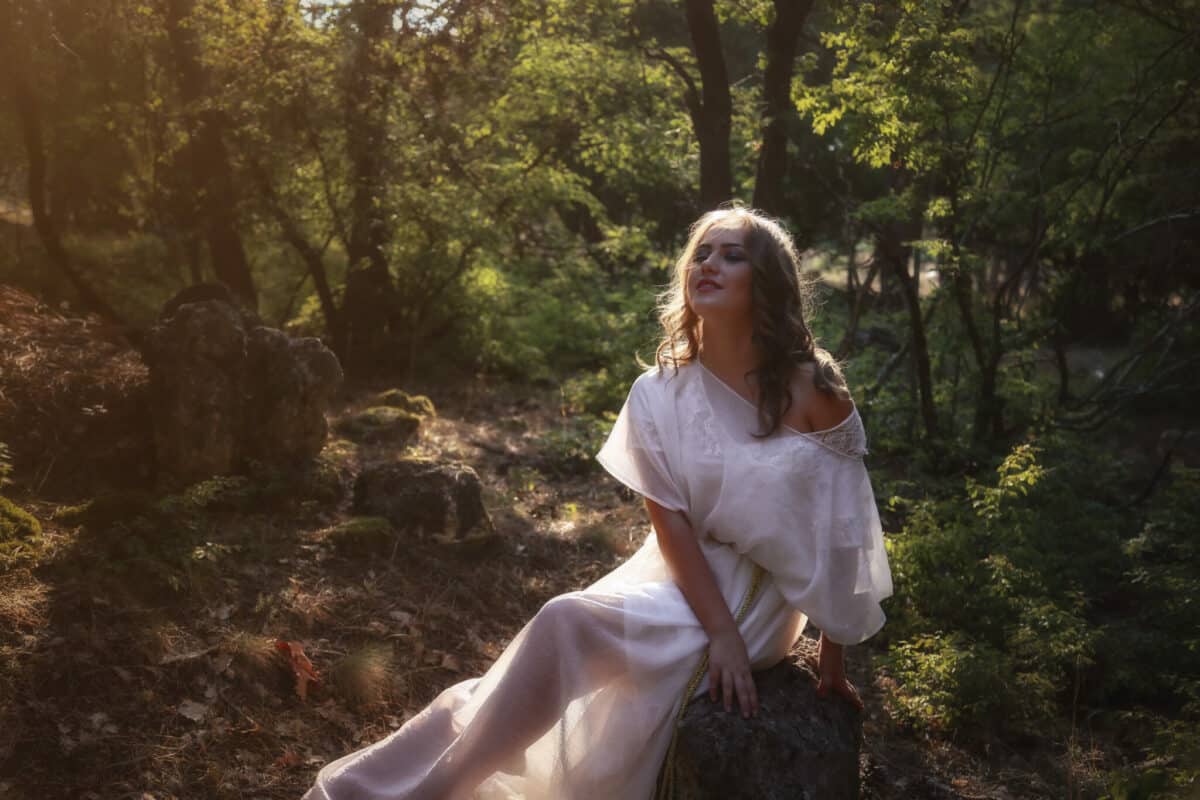 mysterious woman in long white dress in autumn forest