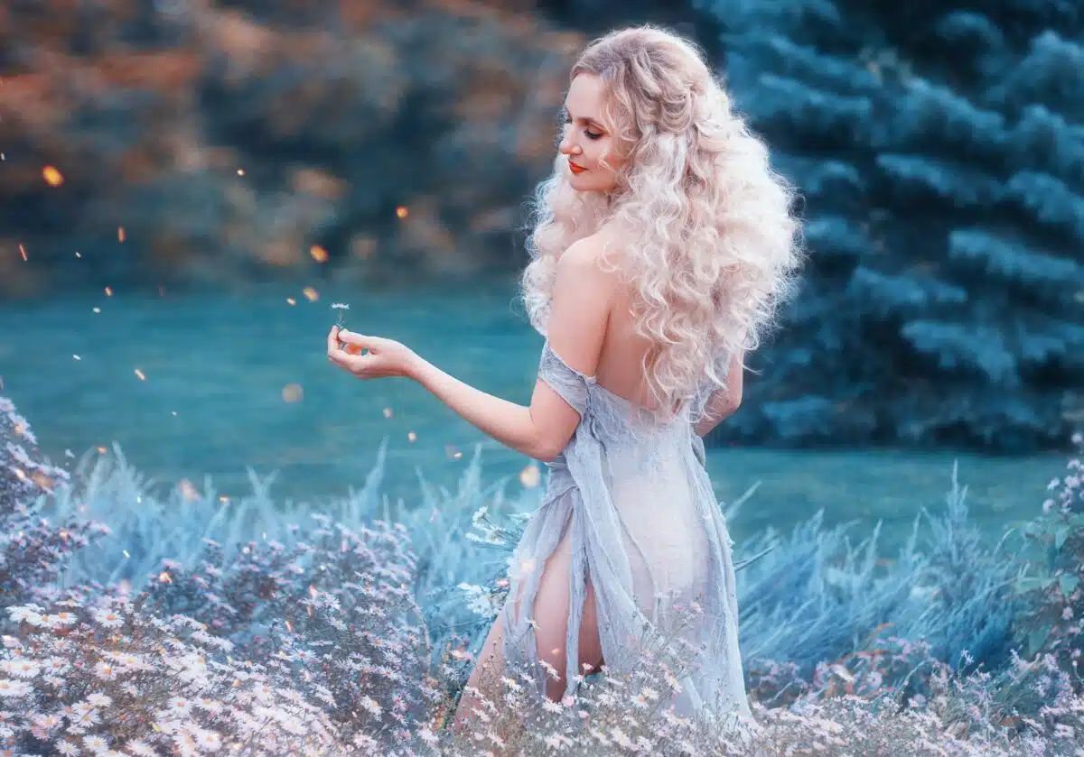 a beautiful blonde nymph picking some wildflowers in the woods