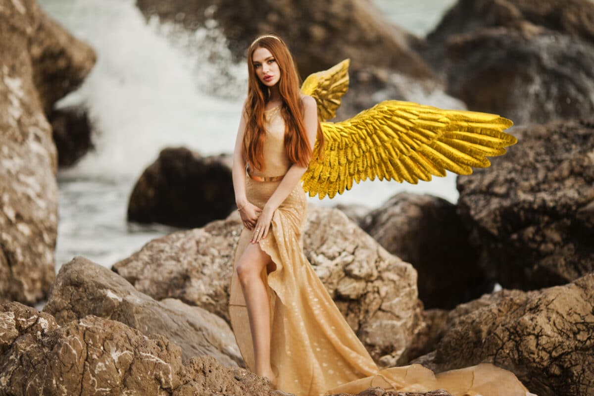 Young beautiful woman fallen angel stands on sea beach enjoy nature. costume bird white wings.