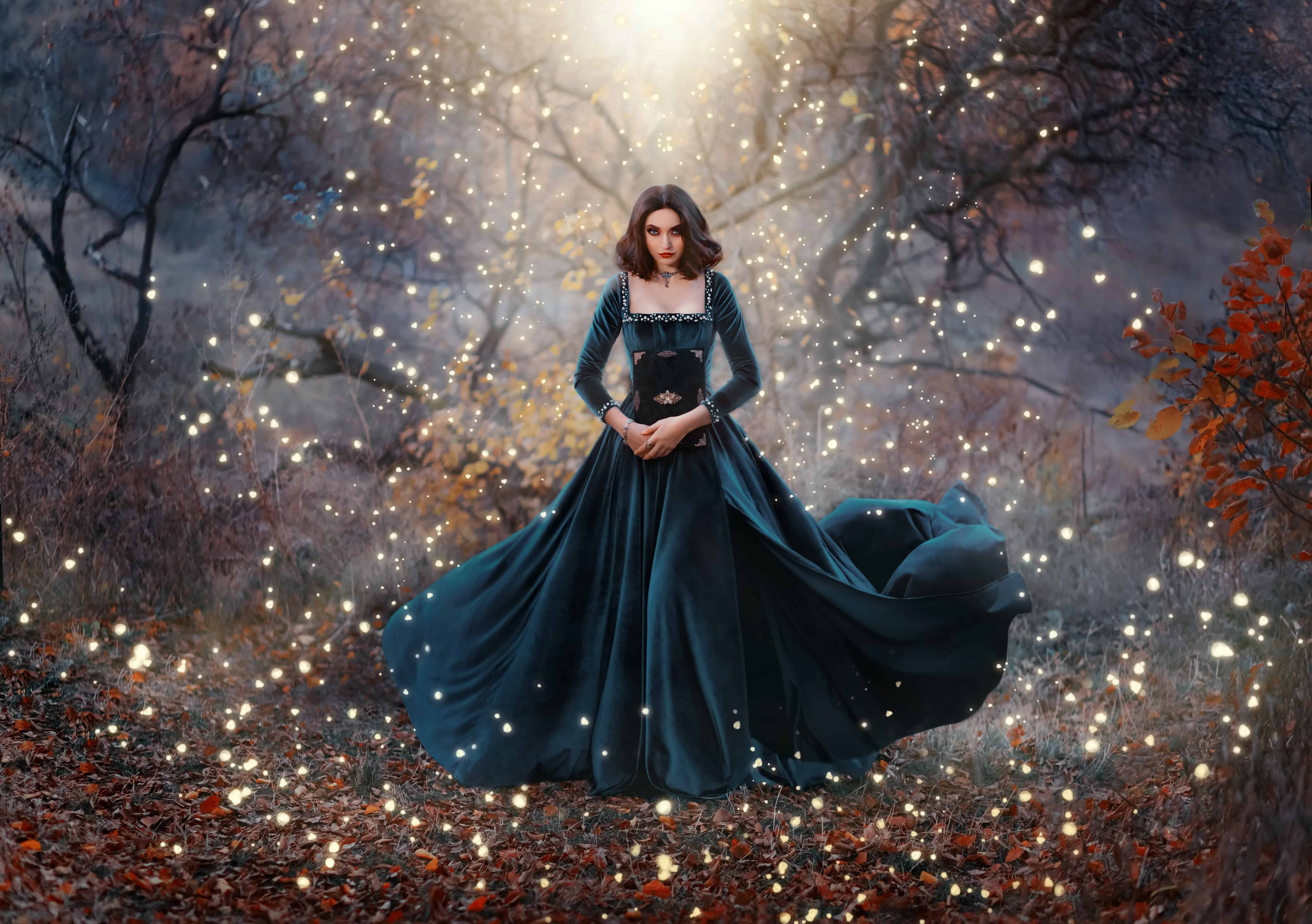Gothic fantasy woman witch holding magic book hands. Long black velvet medieval vintage dress flies wind. Girl conjures. Bright divine light glow sparkles magic circle around lady. Autumn forest tree. 