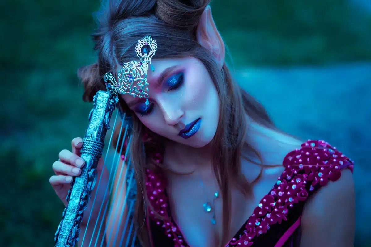 Beautiful but sad young elf woman holding a musical instrument outdoor