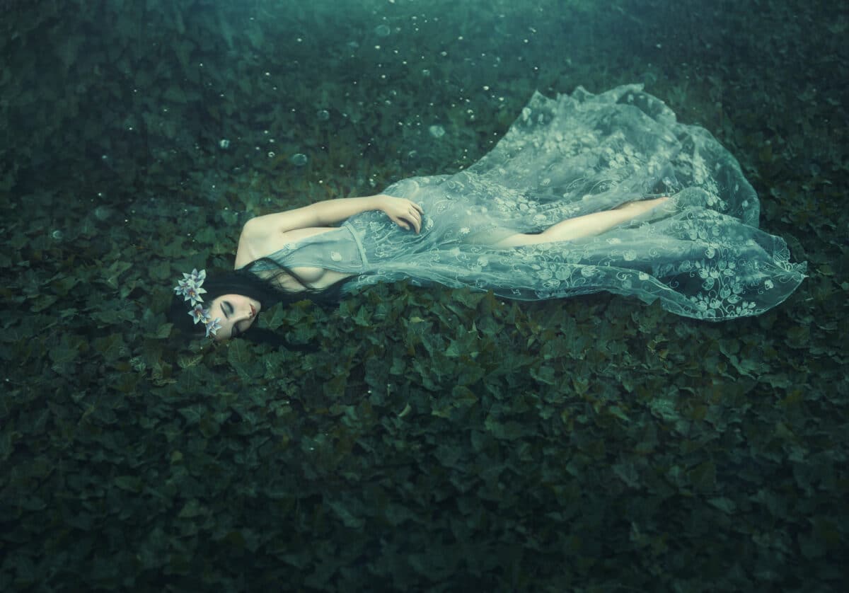 Sleeping Beauty. The girl lies on the grass in a dark, dense for