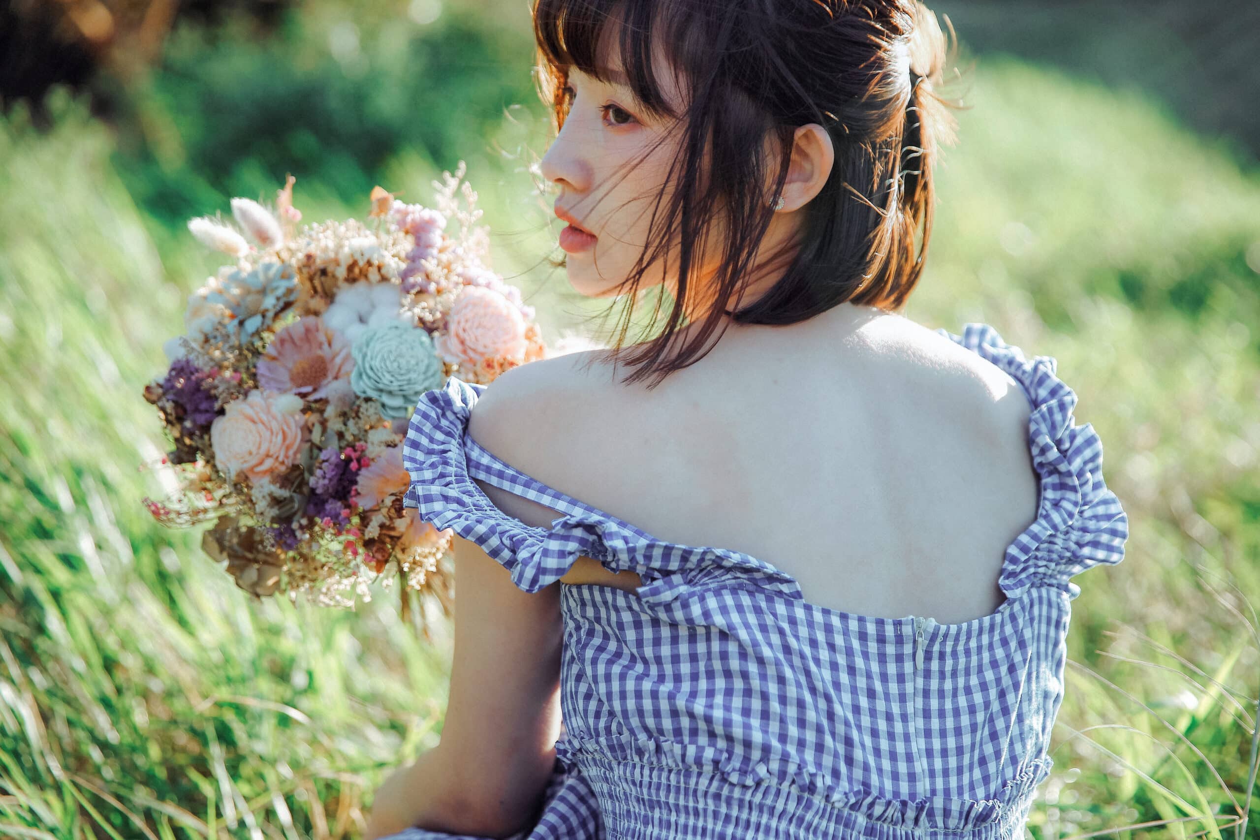 thoughtful Asian girl holding a bouquet of flowers outdoor