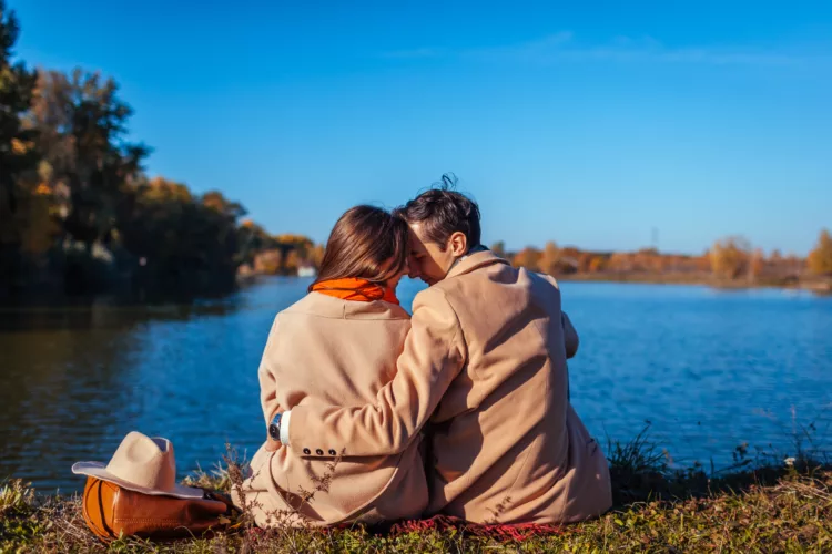 Young couple in love chilling by autumn lake
