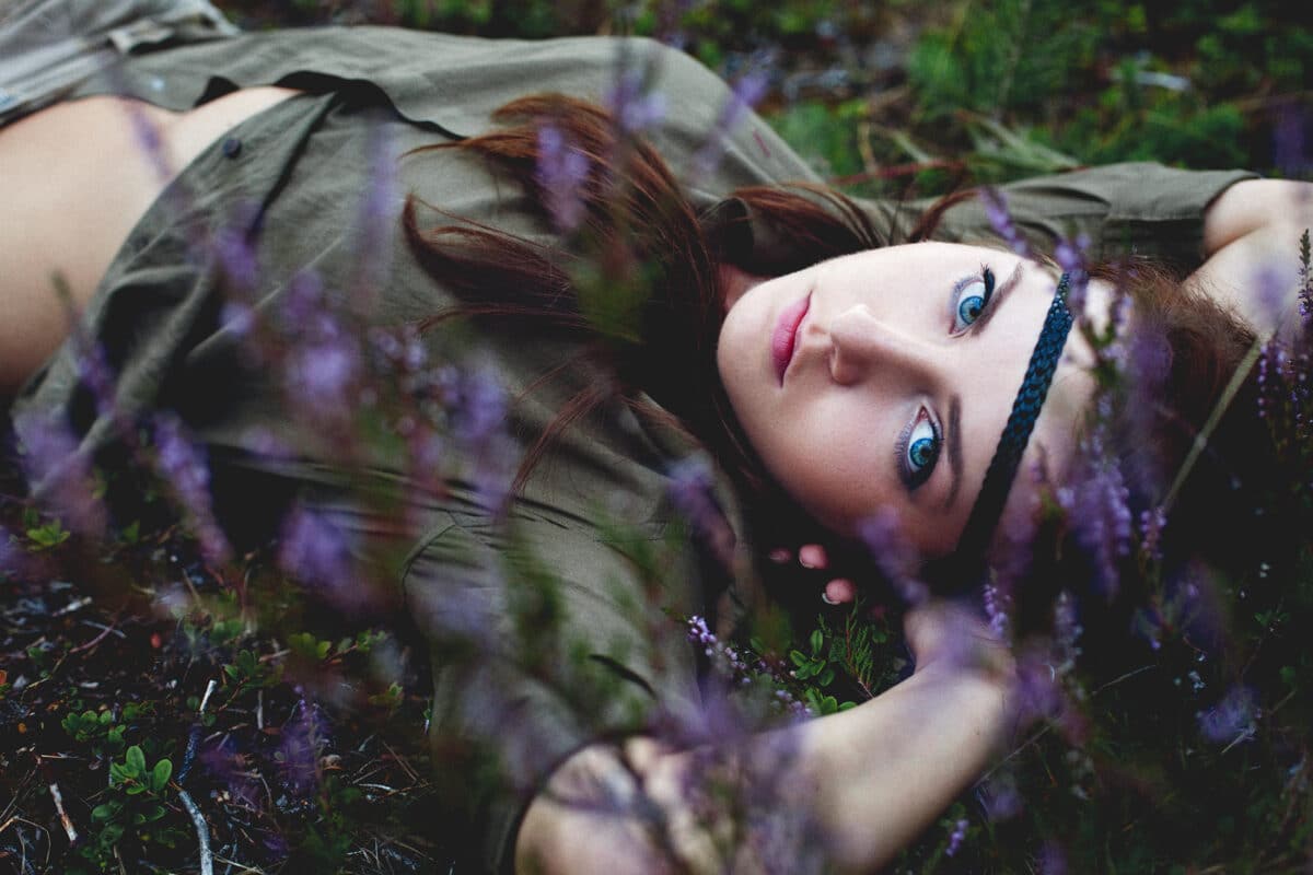 A beautiful blue eyed woman laying down among purple heather
