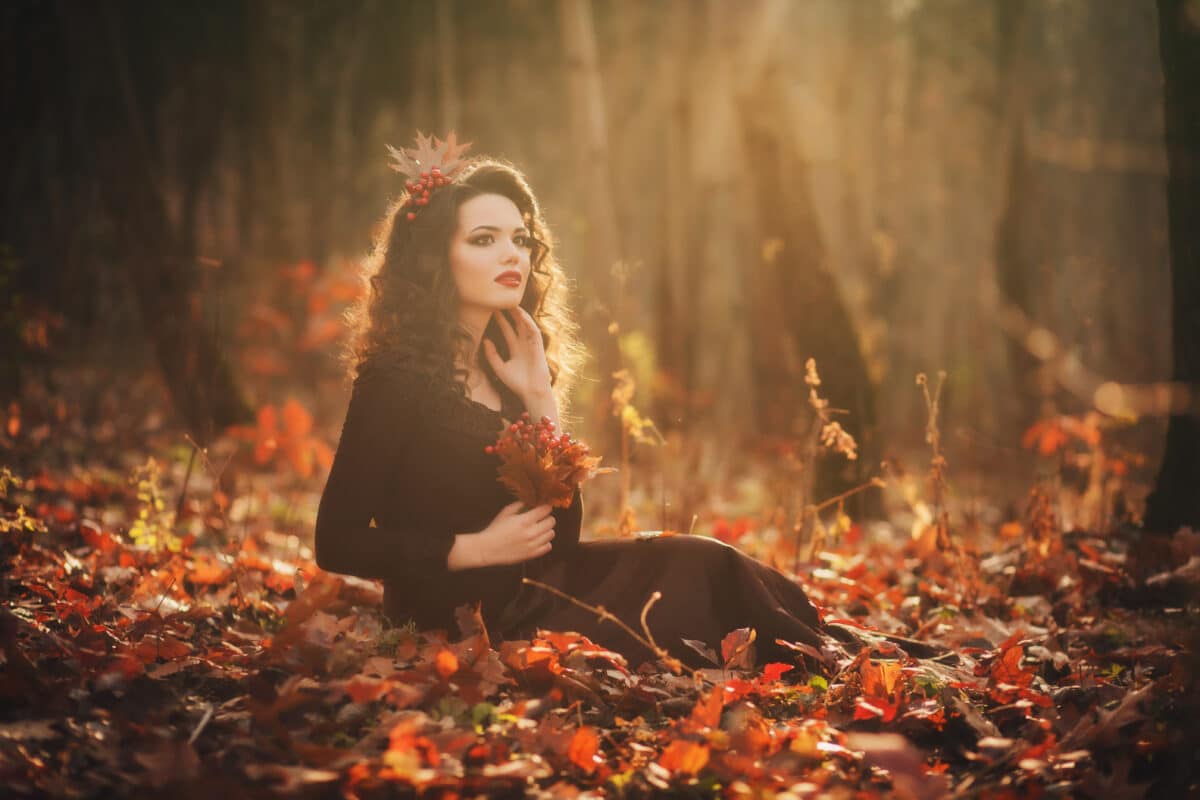 Portrait of romantic girl in a mysterious forest at sunset