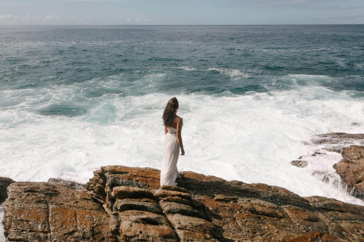 Aerial drone view of bride in an amazing dress standing on a cliff