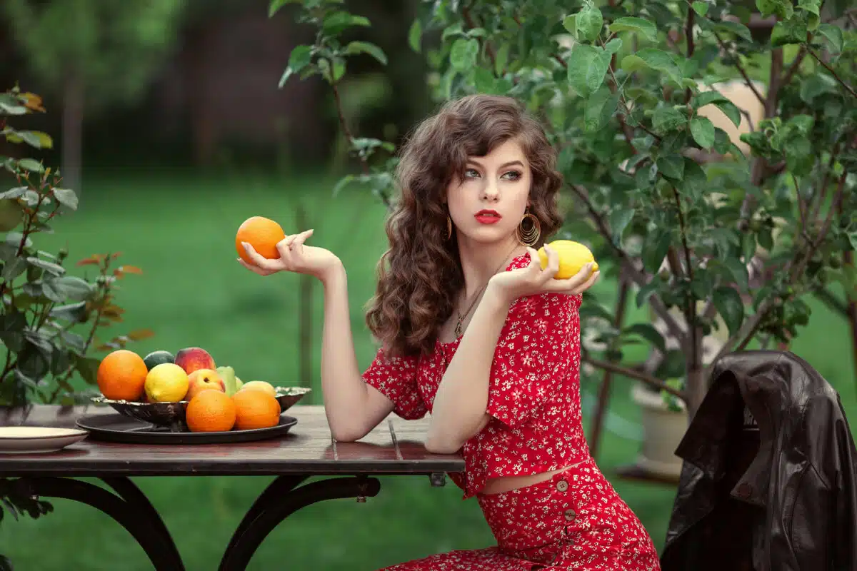 beautiful girl in a red dress with fruit in her hands