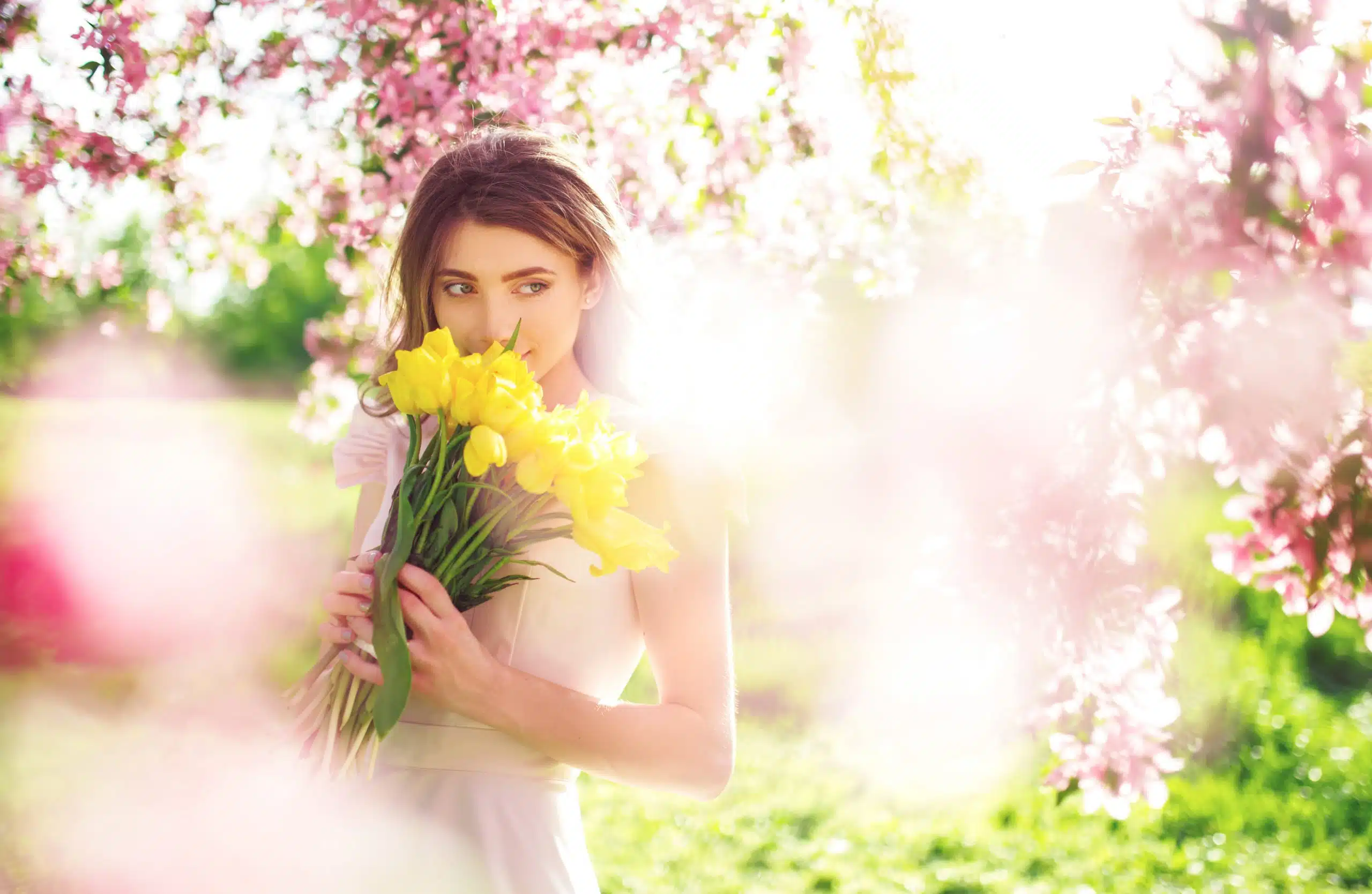 Beautiful young woman enjoying the flowers in spring.