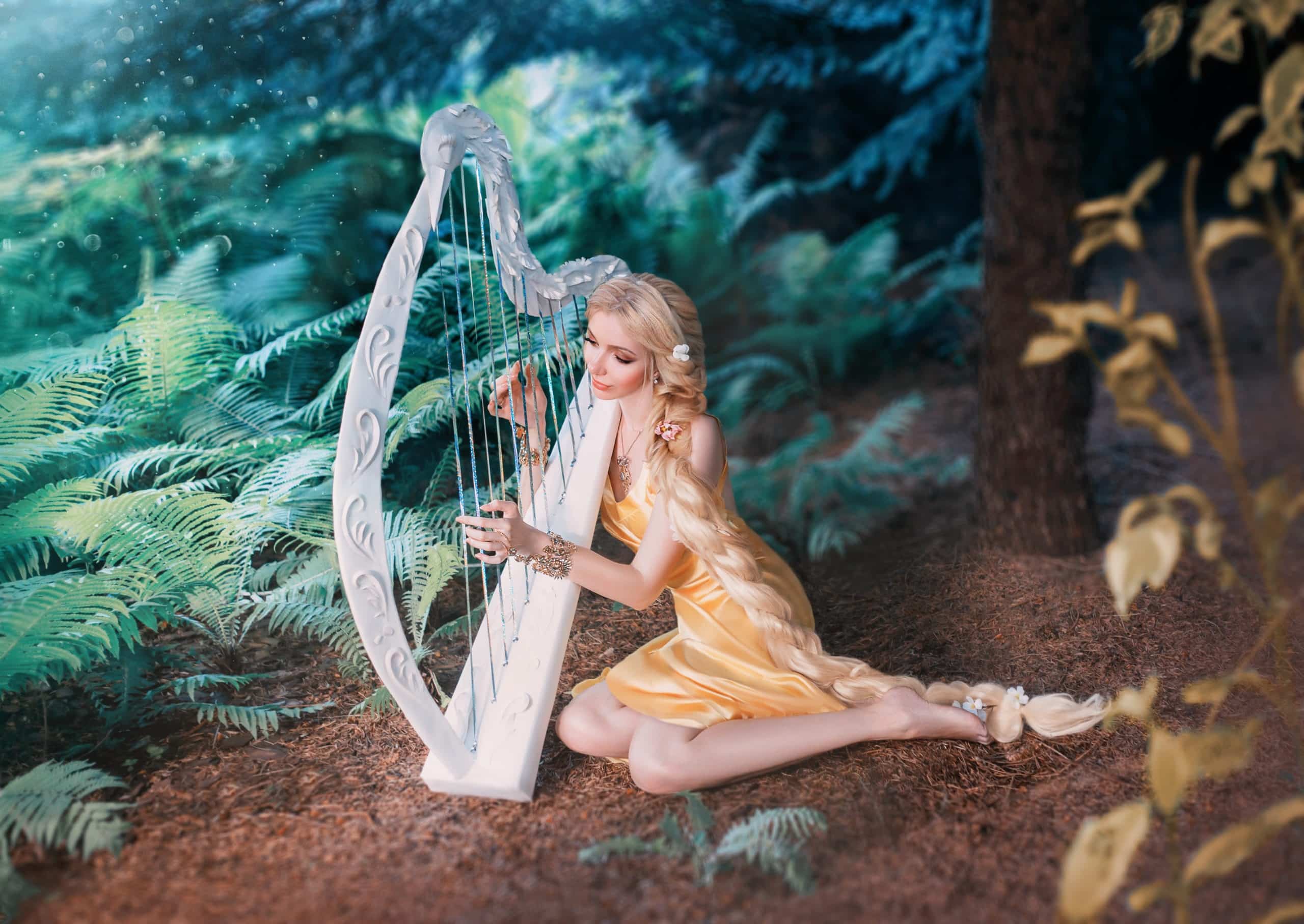 Enchanting woman with long blond hair playing a lyre in the forest.